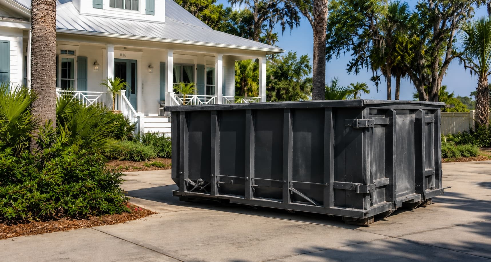 A Golden Isles Junk Removal roll-off dumpster delivered to a residential driveway for a dumpster rental in Brunswick, Georgia.